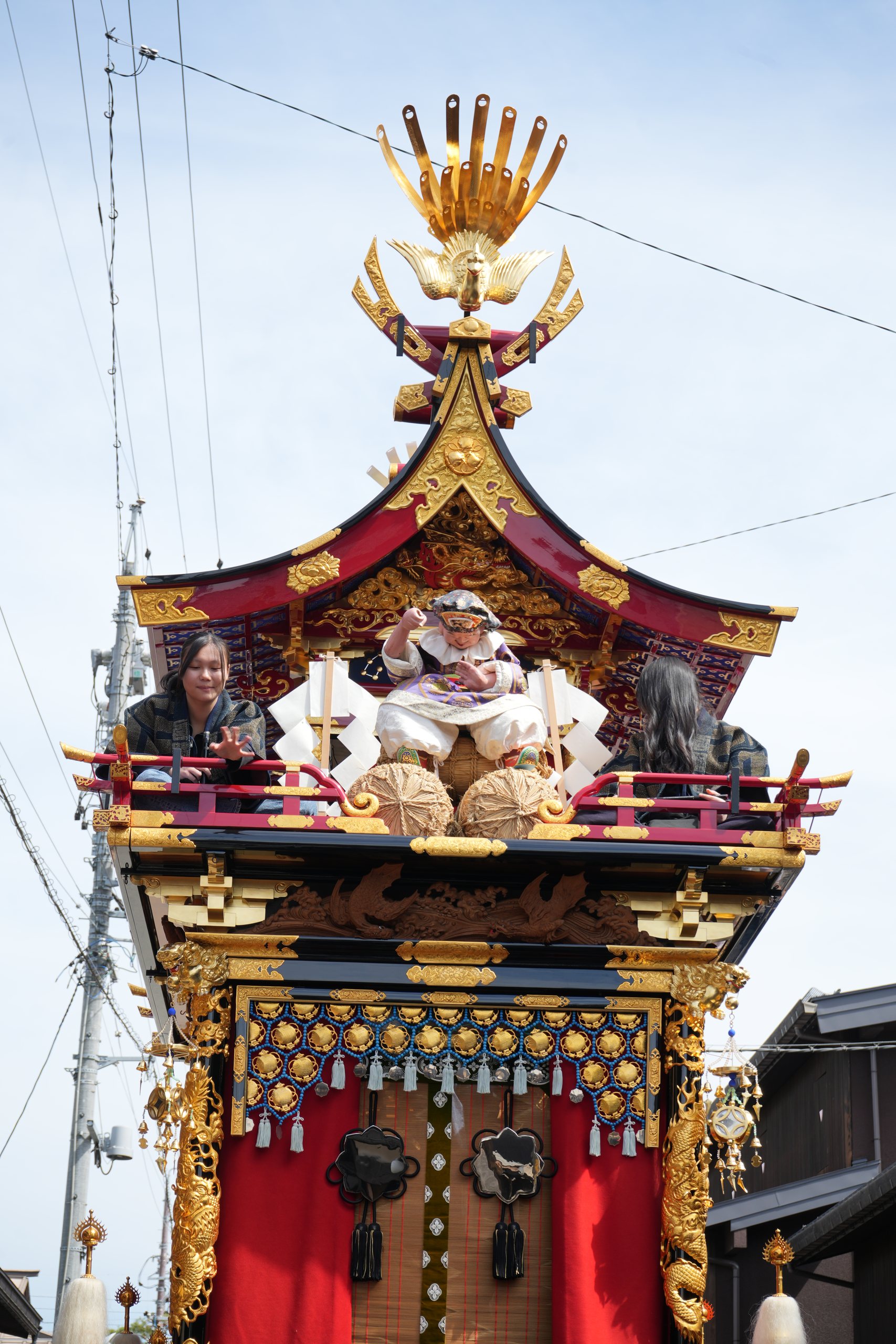 An ornate festival float with gold phoenix and red curtains at the Takayama Spring Festival